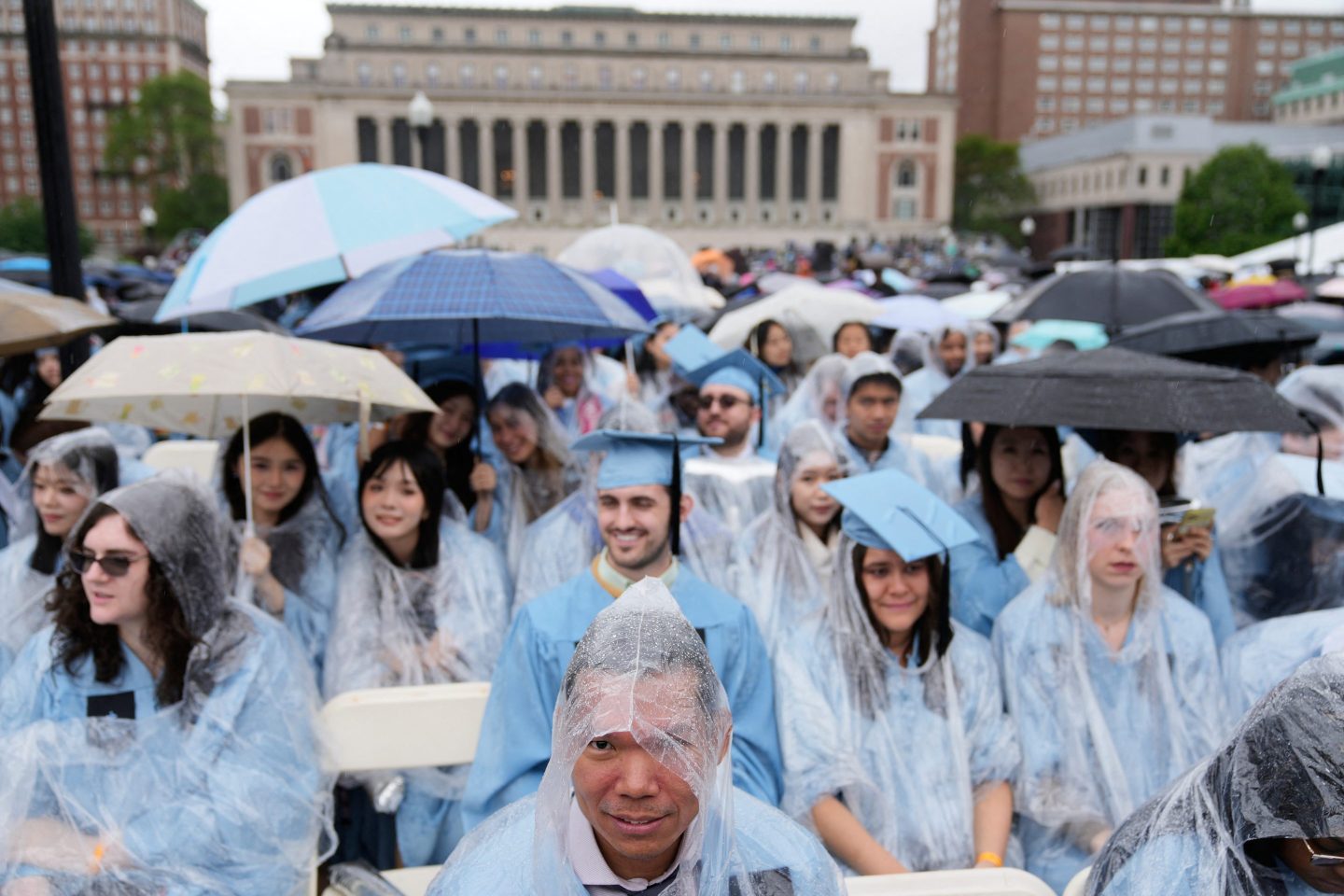 Graduates try to keep the rain off during the Commencement Ceremony at Columbia University in New York on May 21, 2025.