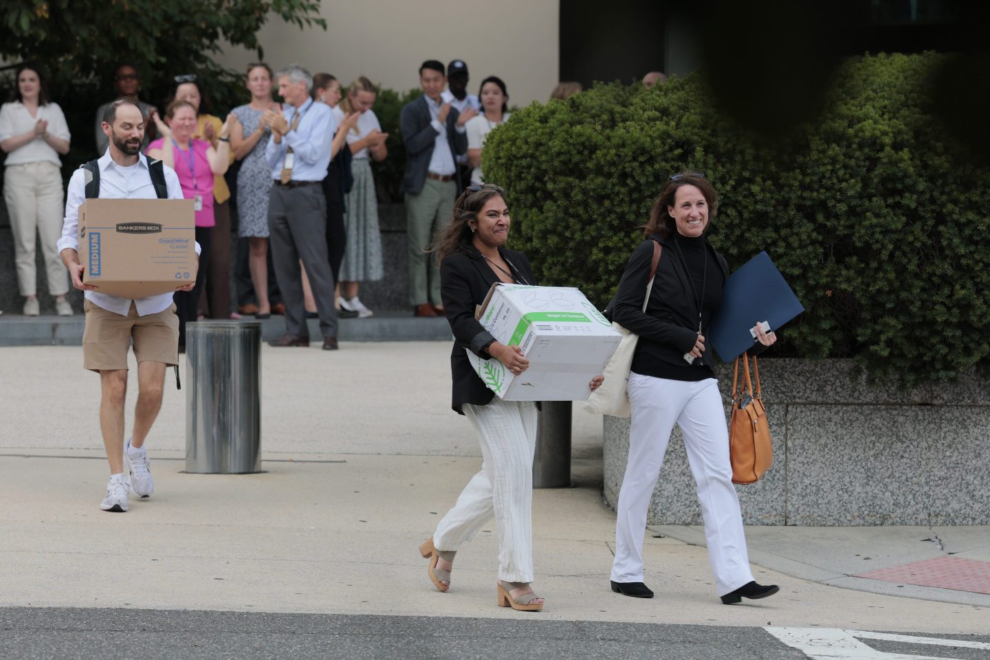 Recently laid off U.S. State Department employees walk out carrying boxes from the Harry S. Truman Federal Building on July 11, 2025 in Washington, DC.