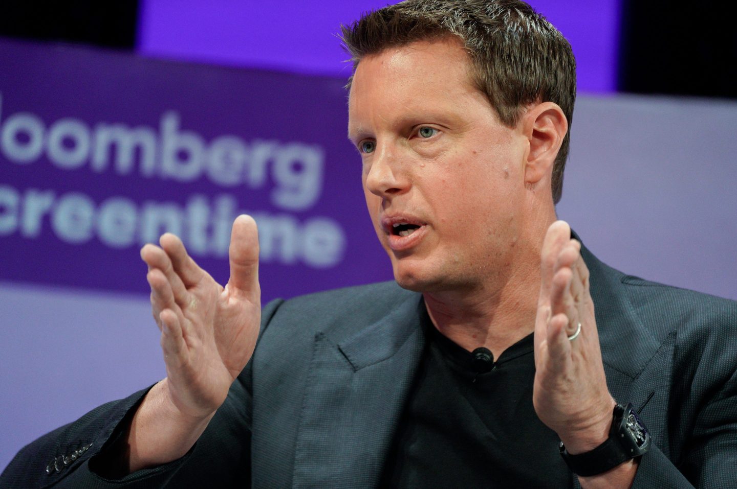 David Ellison, in front of a purple background, puts both hands in front of himself as if measuring something.