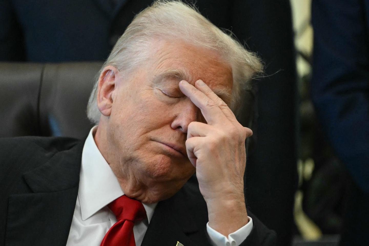 Trump closes his eyes and puts two fingers to his brow.