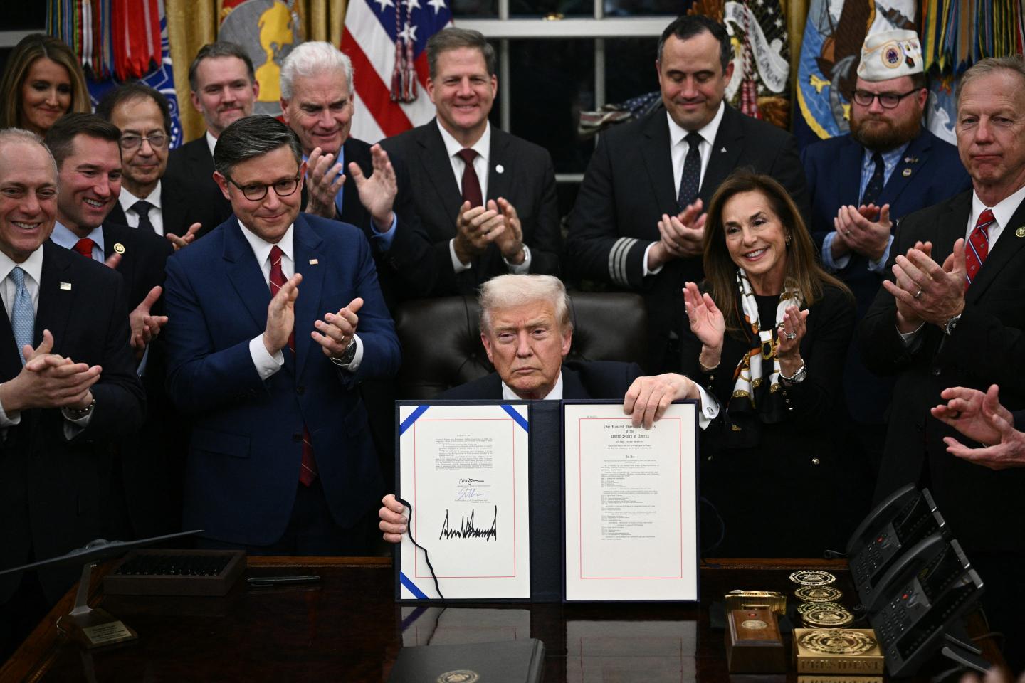 US President Donald Trump shows the signed bill package to re-open the federal government in the Oval Office of the White House in Washington, DC, on November 12, 2025.