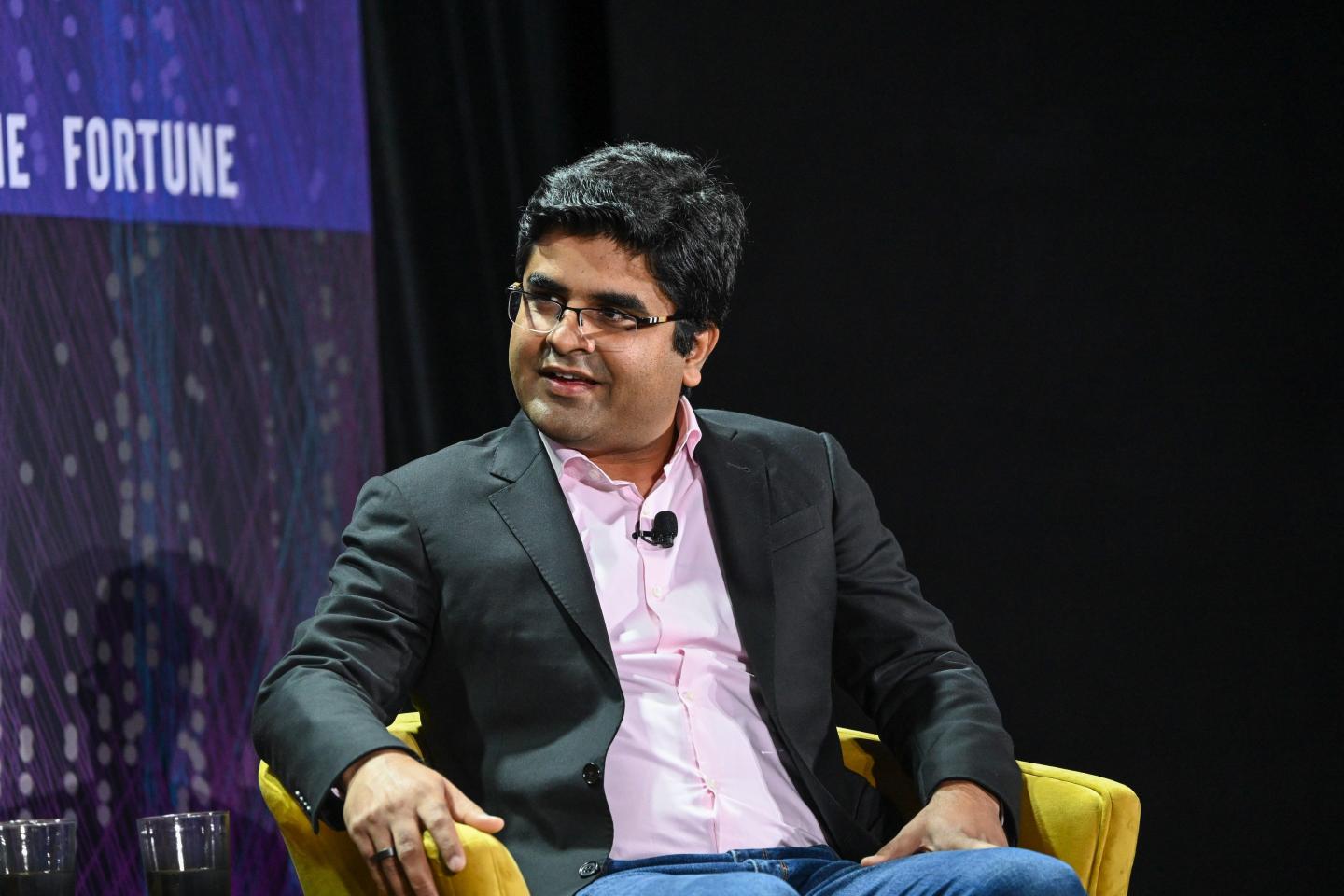 Prakhar Mehrotra smiles as he sits in a yellow chair onstage with "Fortune" on the background screen.