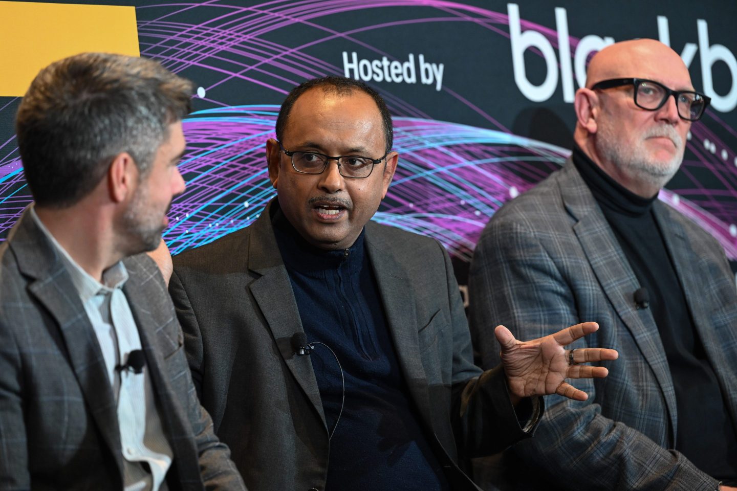 three men in suits, one gesturing