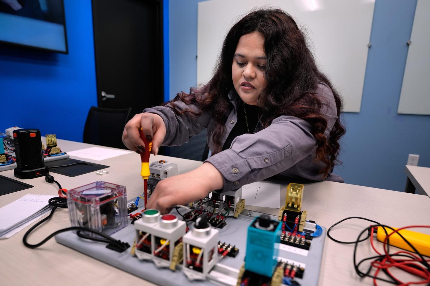 Maintenance technician Liz Cardenas completes a task on an electronics test platform at a training area in a Walmart distribution center Thursday, Sept. 25, 2025, in Bentonville, Ark.
