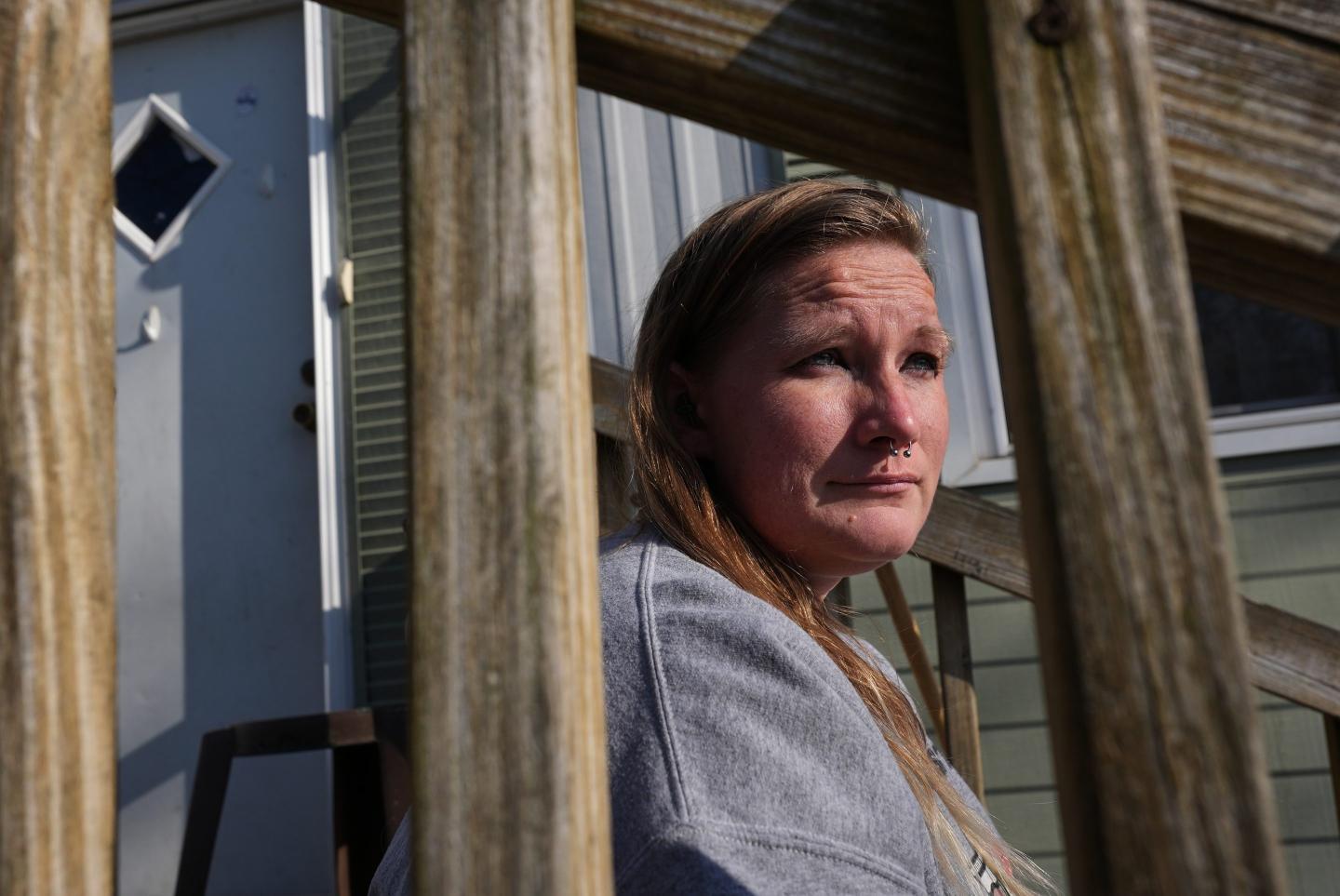 Dianna Tompkins sits on a stair in front of her home in Demotte, Ind., Dec. 17, 2025.