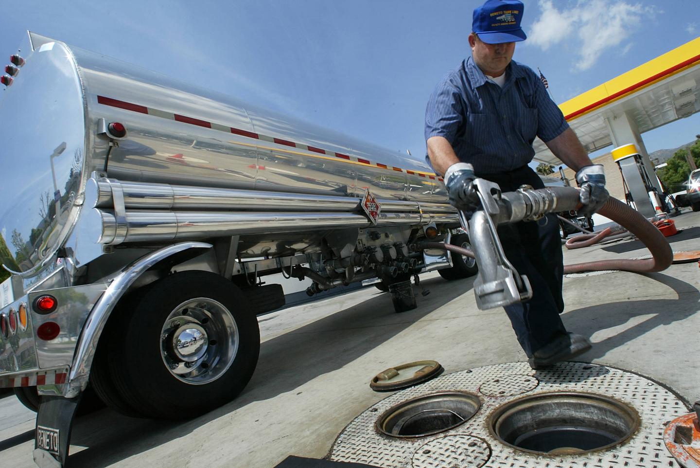 Gasoline delivery truck driver Robert Clark prepares to fill the underground gas tanks at a Shell station in Glendale California. Fuel prices in December 2025 are the lowest since the pandemic in early 2021.