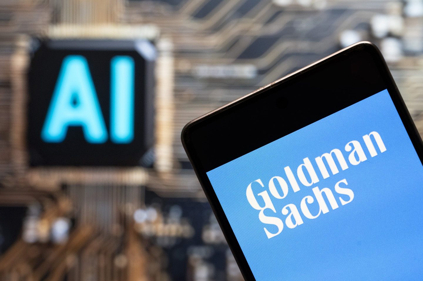 Goldman Sachs' logo seen displayed on a smartphone with an AI chip and symbol in the background.