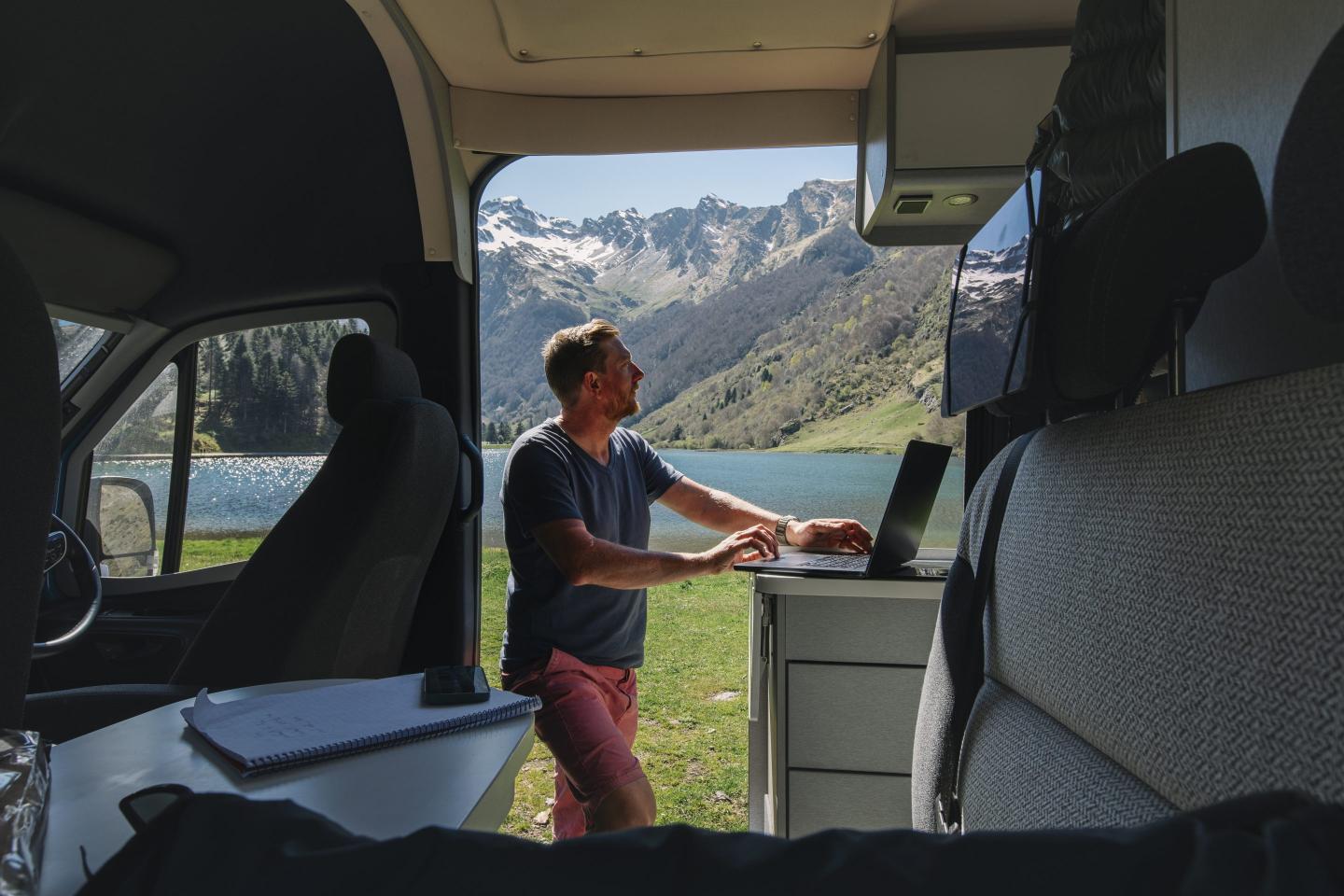 A man works on a laptop in a camper van