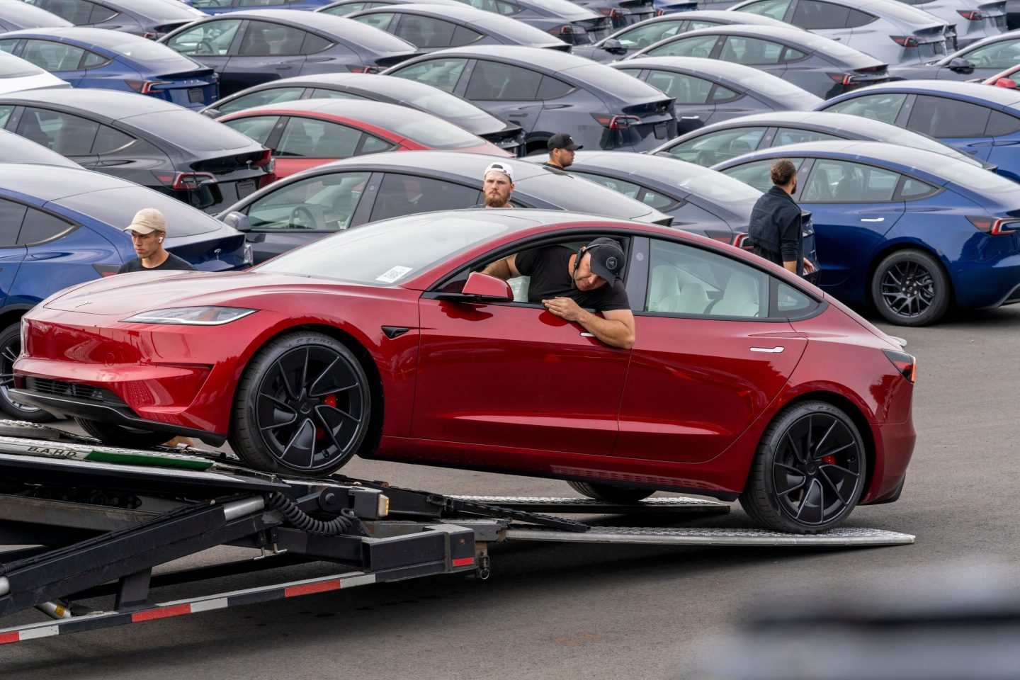 A worker unloads a new Tesla Model 3 from a truck at a logistics drop zone in Seattle, Washington, US, on Thursday, Aug. 22, 2024. The world's largest seller of battery-electric vehicles is well off its pace of 1.8 million deliveries last year and reiterated that volume growth will be notably lower in 2024. Photographer: M. Scott Brauer/Bloomberg via Getty Images