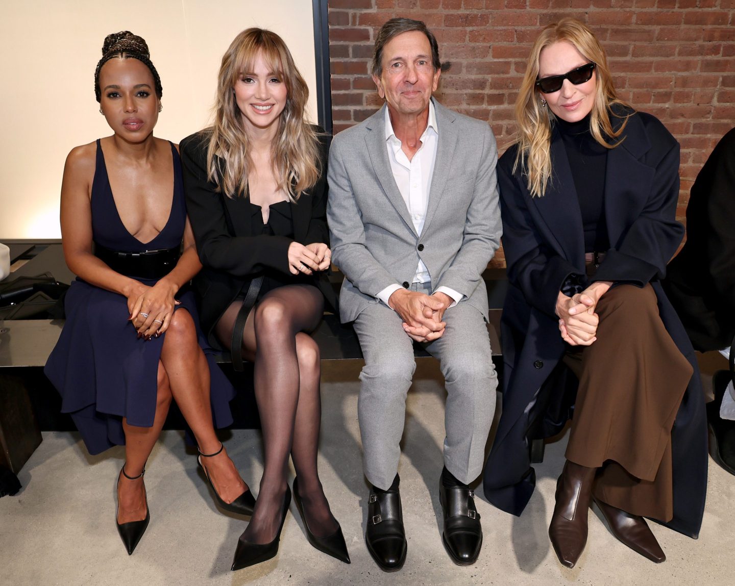 Three women and one man in a suit sitting on a bench.