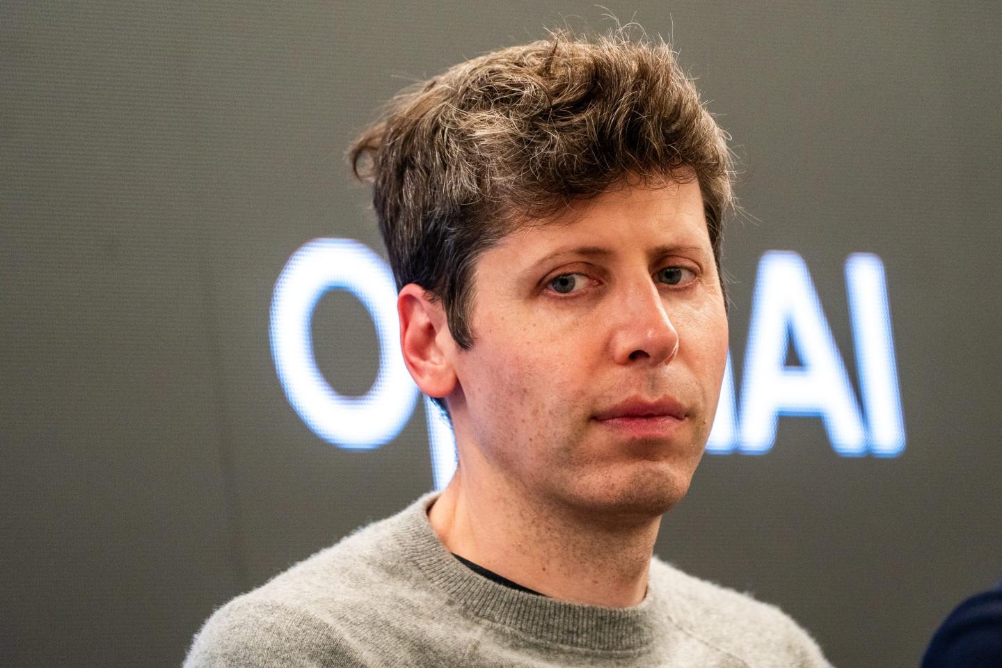 Sam Altman looks down and to the side, frowning.
