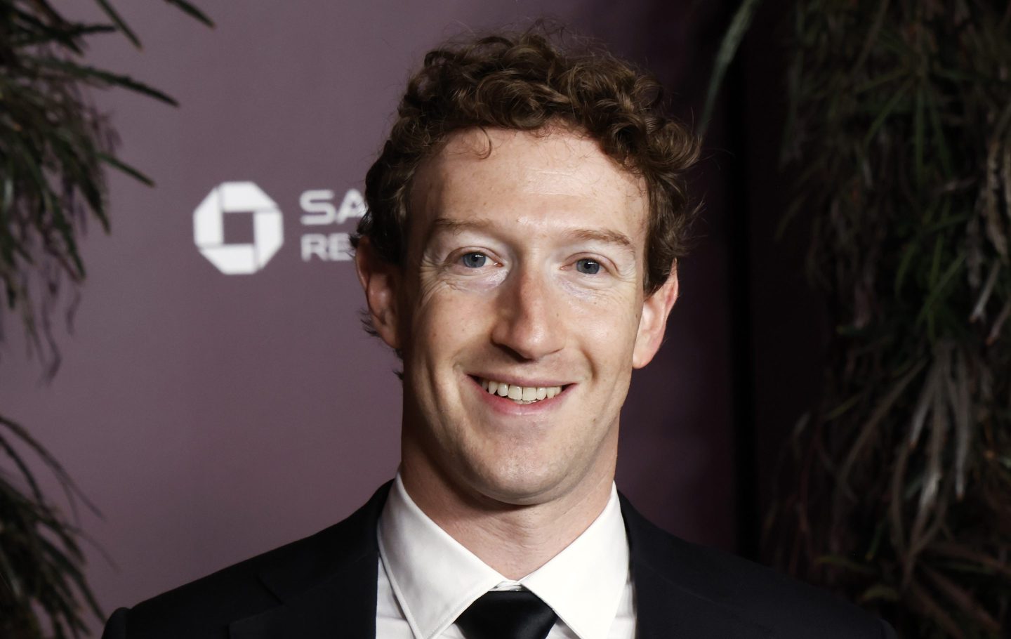 Mark Zuckerberg smiles in a black and white suit