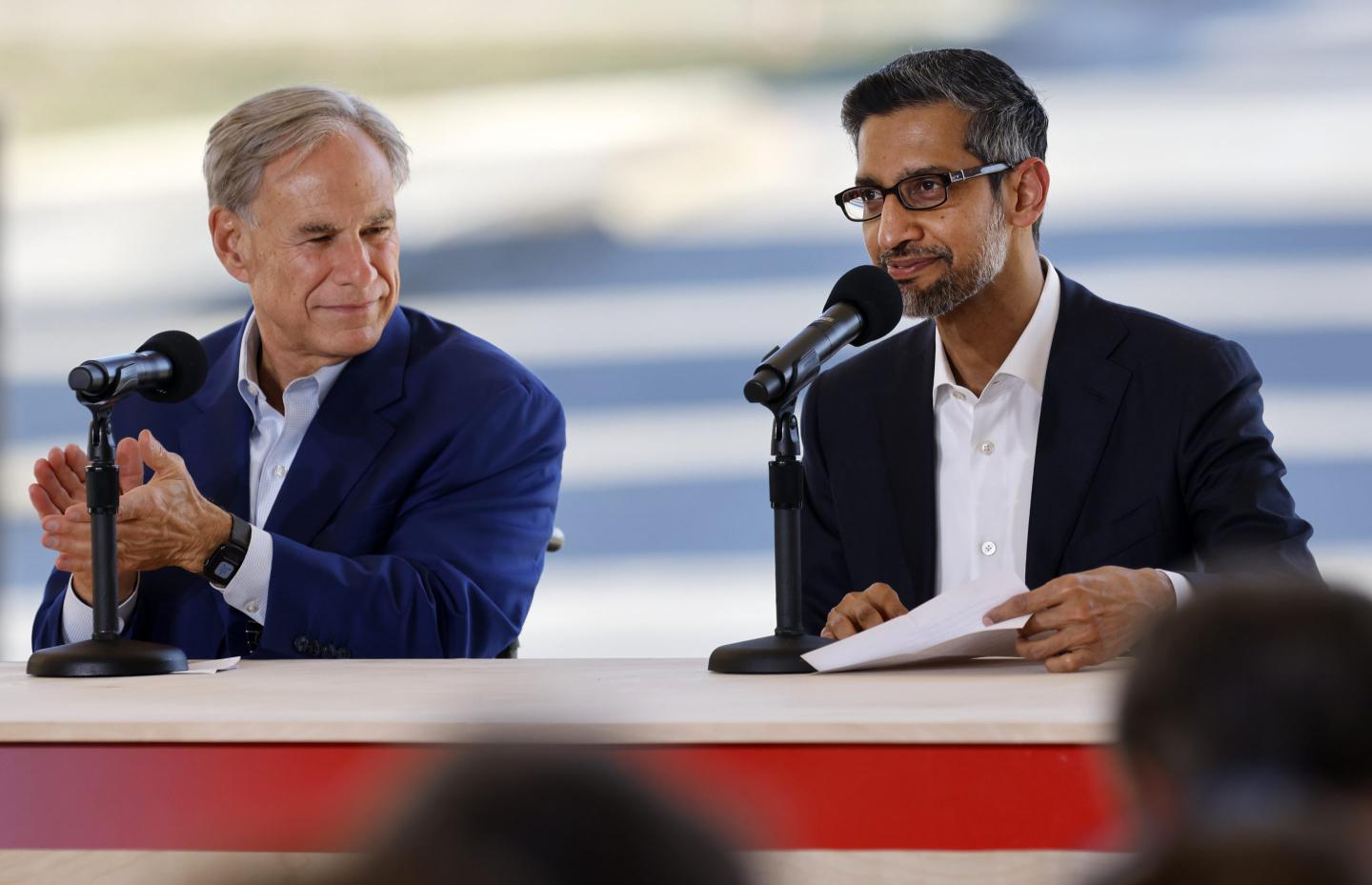 Greg Abbott and Sundar Pichai sit next to each other at a red table.