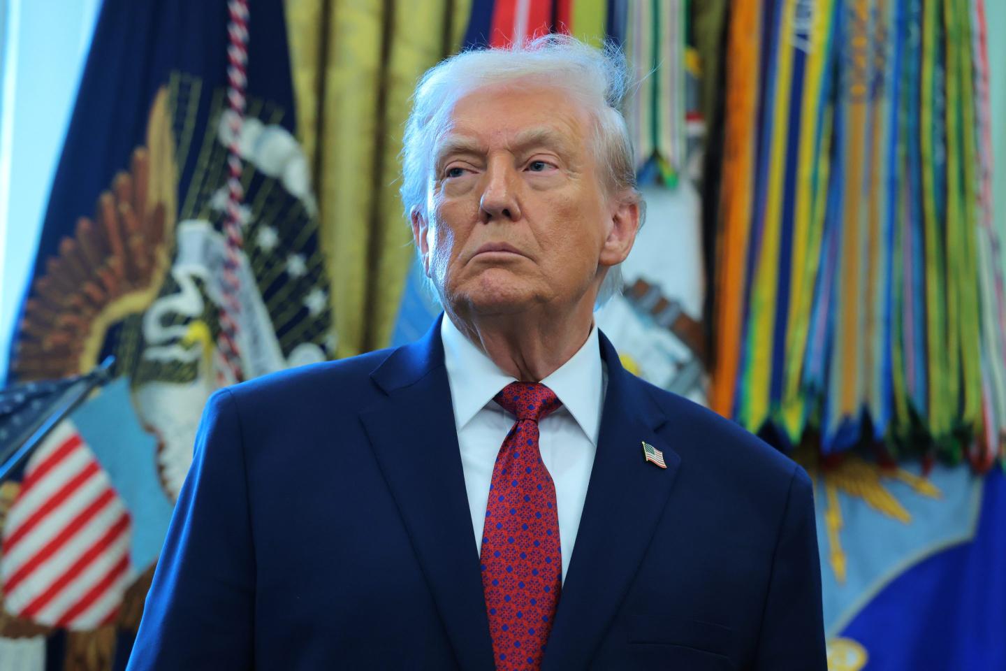 Donald Trump, standing in the Oval Office, frowns and looks to the side.