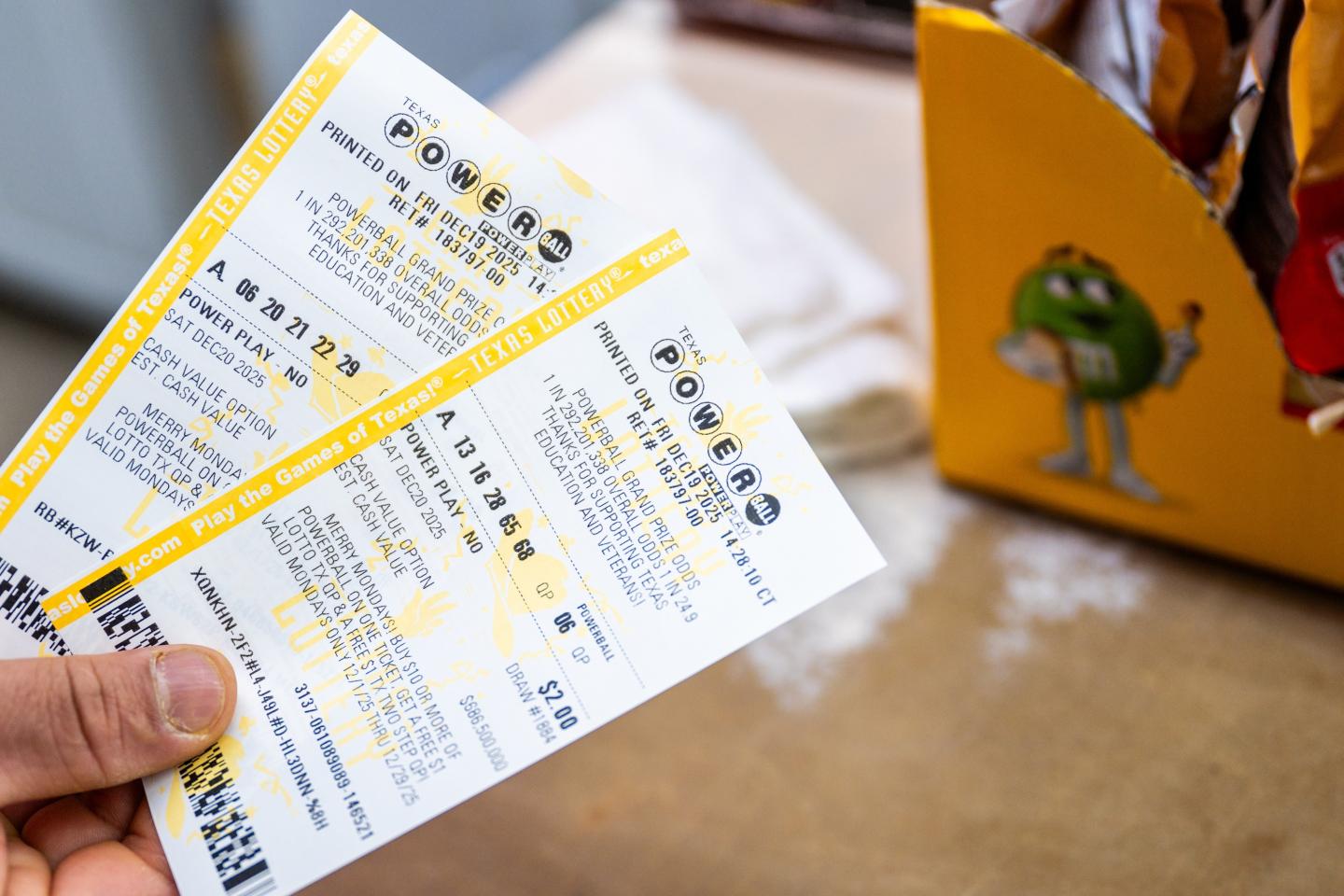 In this photo illustration, a clerk holds Powerball lottery tickets at a convenience store