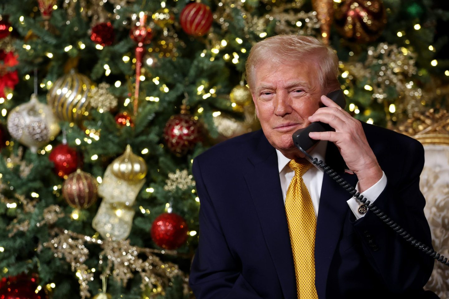 Donald Trump on the phone in front of a Christmas tree