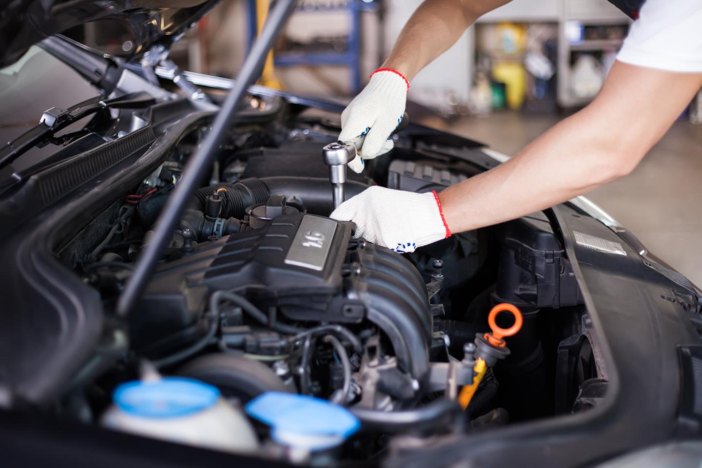 Photo of a car mechanic's hands fixing an engine