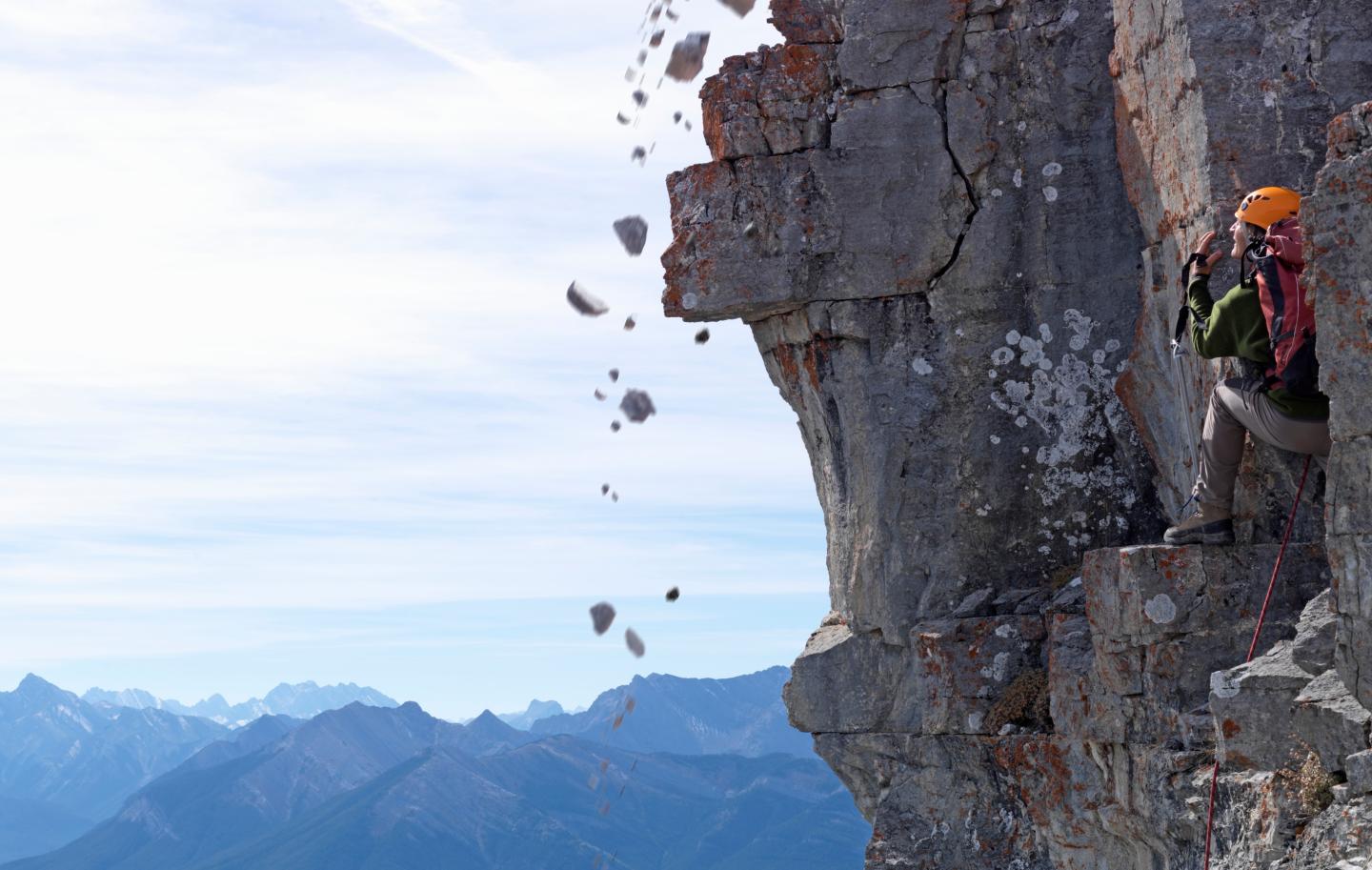 Man climber standing on rock, looking at falling stones