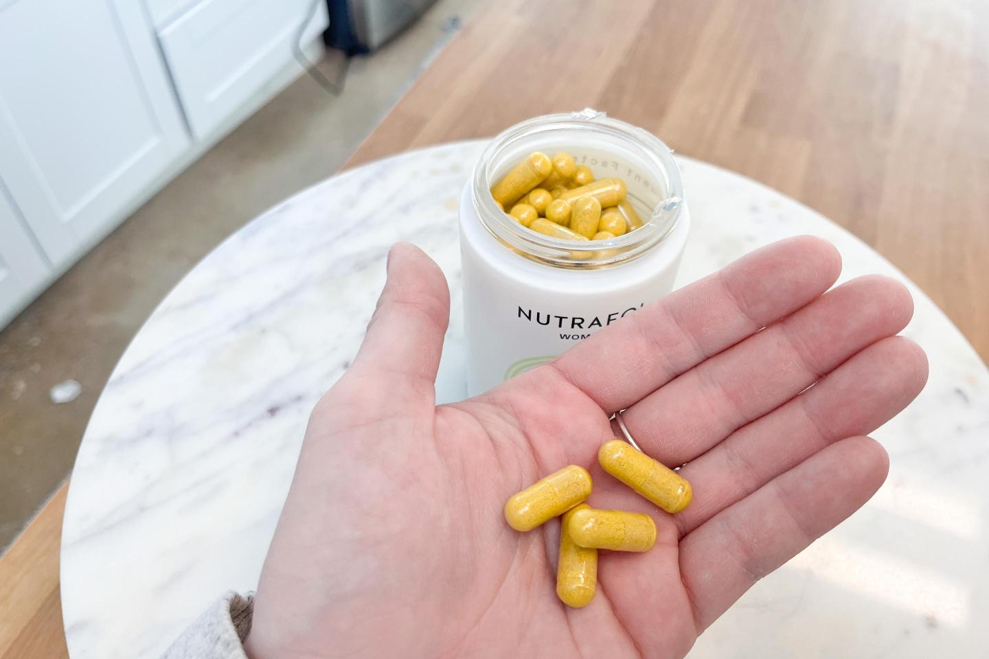Our tester holds out Nutrafol capsules.