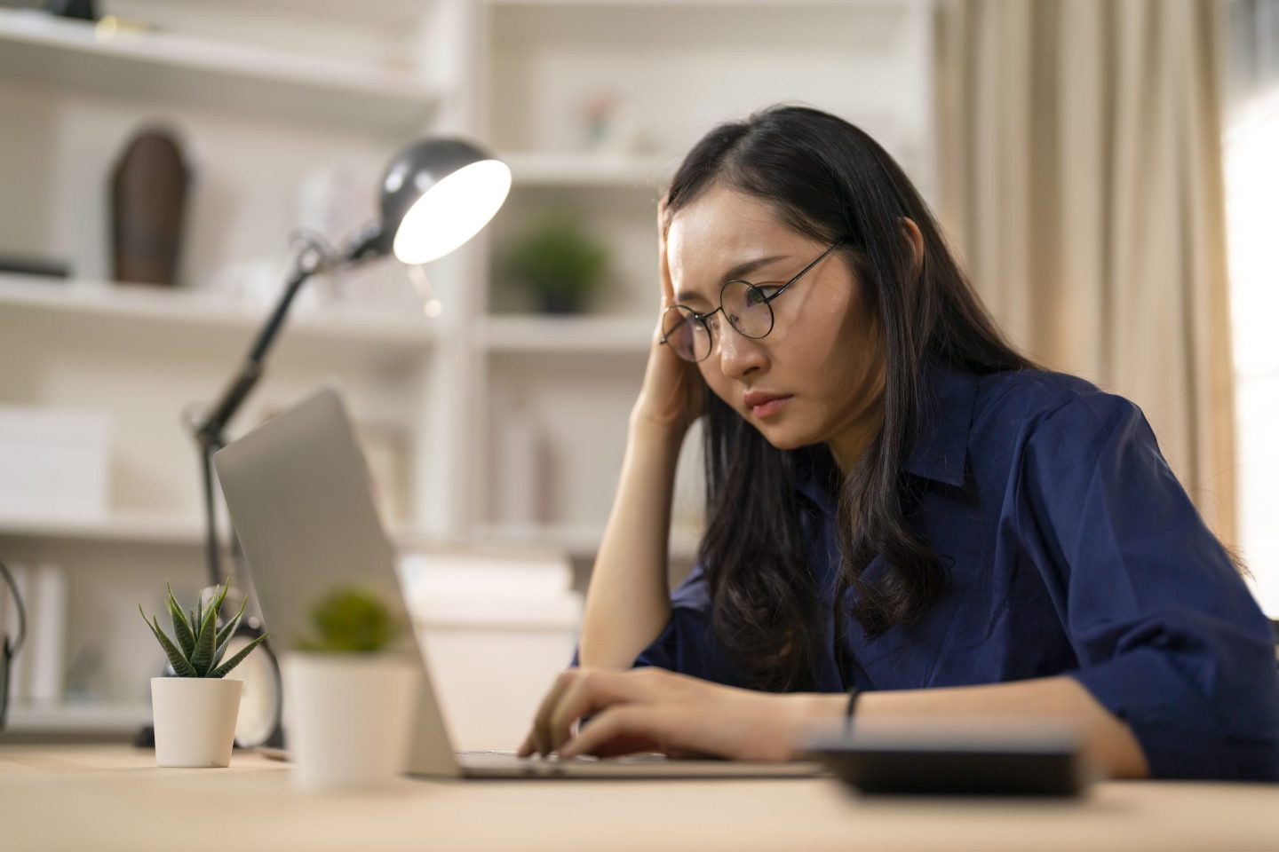Women sits at a desk looking at her laptop.