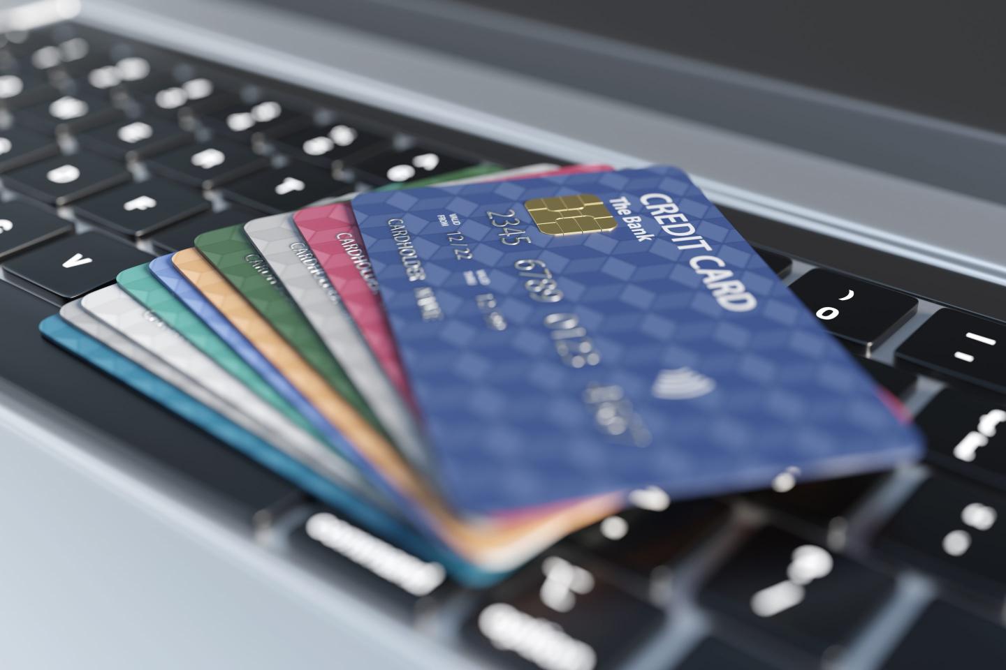 Stack of colorful credit card on a silver laptop.