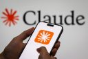A smartphone displaying the app icon for Anthropic AI chatbot Claude displayed against a backdrop that also says "Claude."