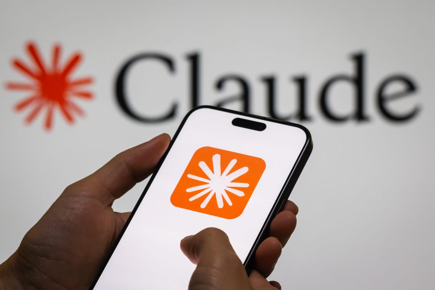 A smartphone displaying the app icon for Anthropic AI chatbot Claude displayed against a backdrop that also says "Claude."