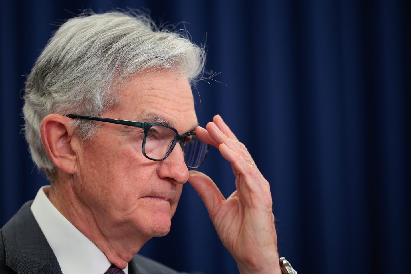 Jerome Powell adjusts his glasses, looking to his left.