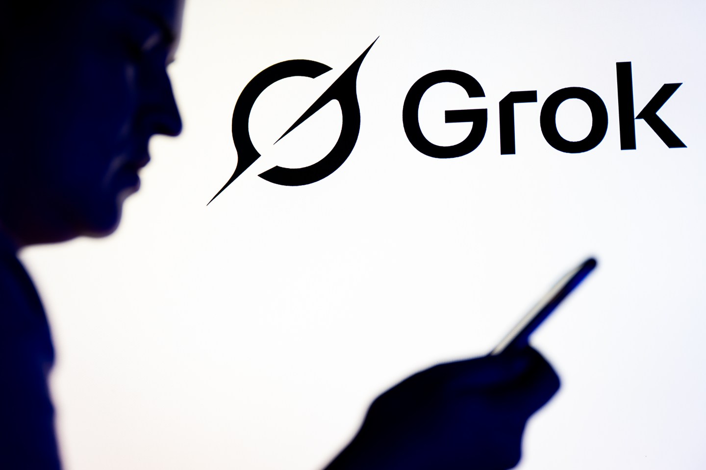 Grok logo with hand holding phone.