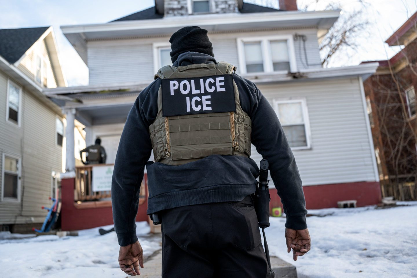 A federal law enforcement agent outside a home during a raid in south Minneapolis, Minnesota, US, on Tuesday, Jan. 13, 2026. Minnesota officials are suing over the unprecedented surge of US immigration authorities in the state, taking the Trump administration to court days after a federal agent shot and killed a Minneapolis woman. Photographer: Victor J. Blue/Bloomberg via Getty Images