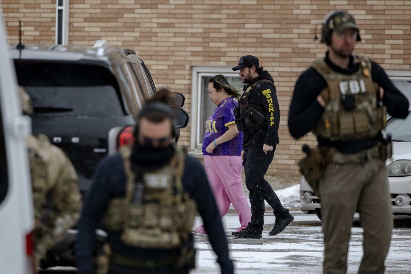 ST. PAUL, MINNESOTA - JANUARY 16: A Minnesota sheriff escorts a woman towards an unmarked vehicle after agents raided her building on January 16, 2026 in St. Paul, Minnesota. According to reports, a federal agent allegedly fatally shot a woman in her car during an incident in south Minneapolis. (Photo by Jim Vondruska/Getty Images)