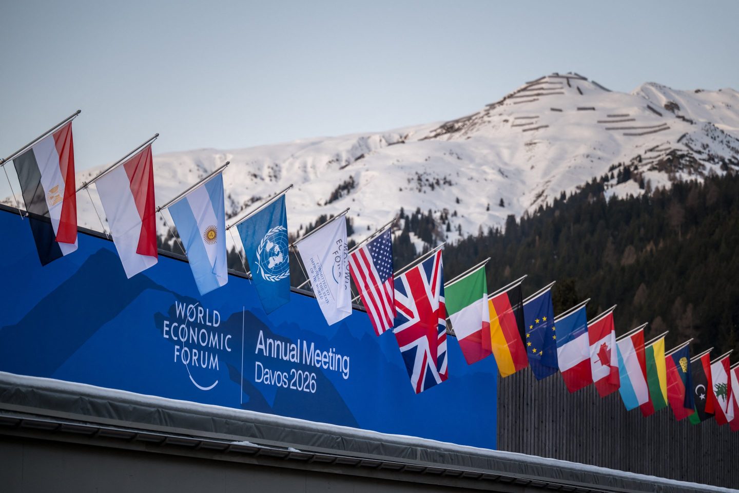 Image of various nation's flags over the World Economic Forum sign in Davos.