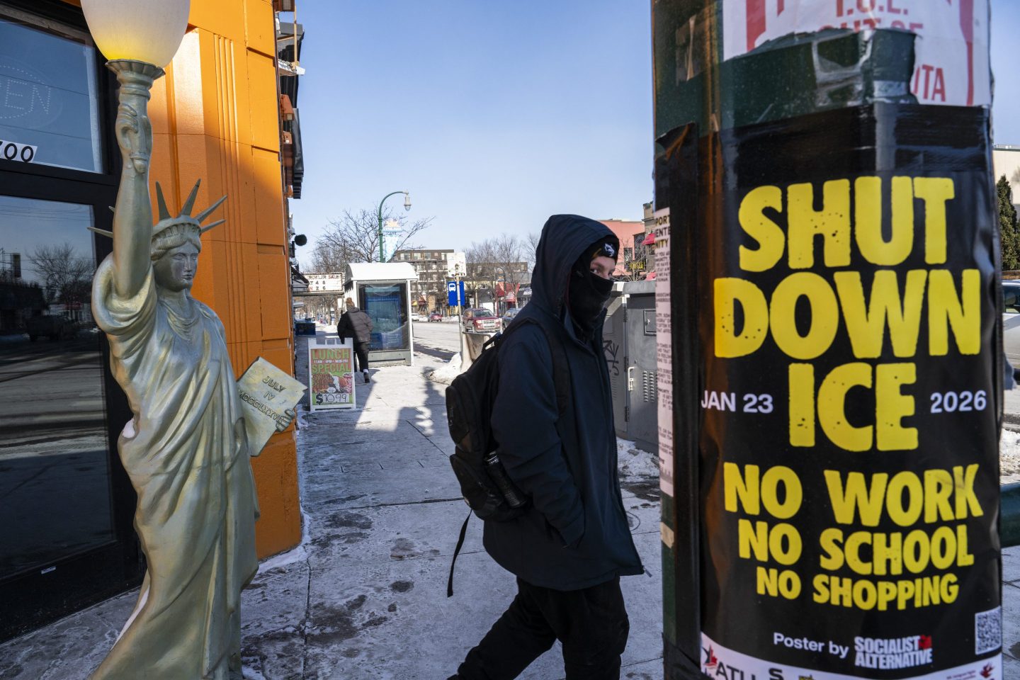 A person walks past a Lady Liberty statue in front of a shuttered gyro shop and a poster calling for a strike of businesses under the banner "ICE out of Minnesota: Day of Truth and Freedom" in Minneapolis, Minnesota, on January 23, 2026. The Pentagon has ordered 1,500 US soldiers to prepare for a possible deployment to a state roiled by unrest over an immigration crackdown, US media reported on January 18. The reported preparations come days after President Donald Trump threatened to invoke the Insurrection Act, which enables use of the military to suppress "armed rebellion" or "domestic violence" -- although a day later he said there was no immediate need for it. (Photo by ROBERTO SCHMIDT / AFP via Getty Images)