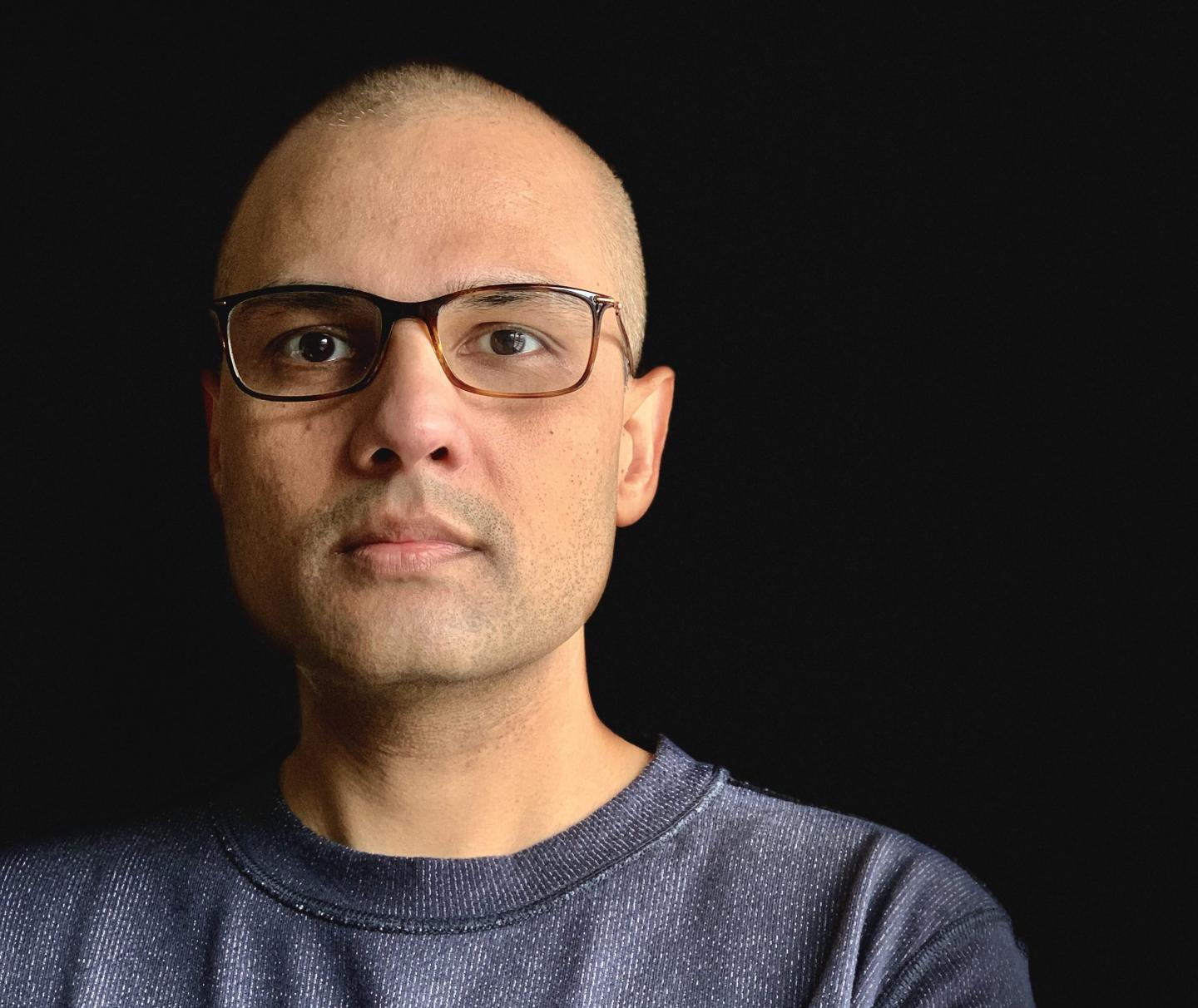 man with glasses stares into camera