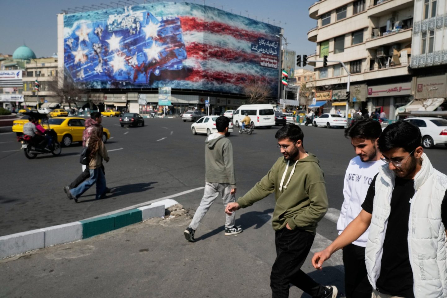 Pedestrians walk past an American flag mural
