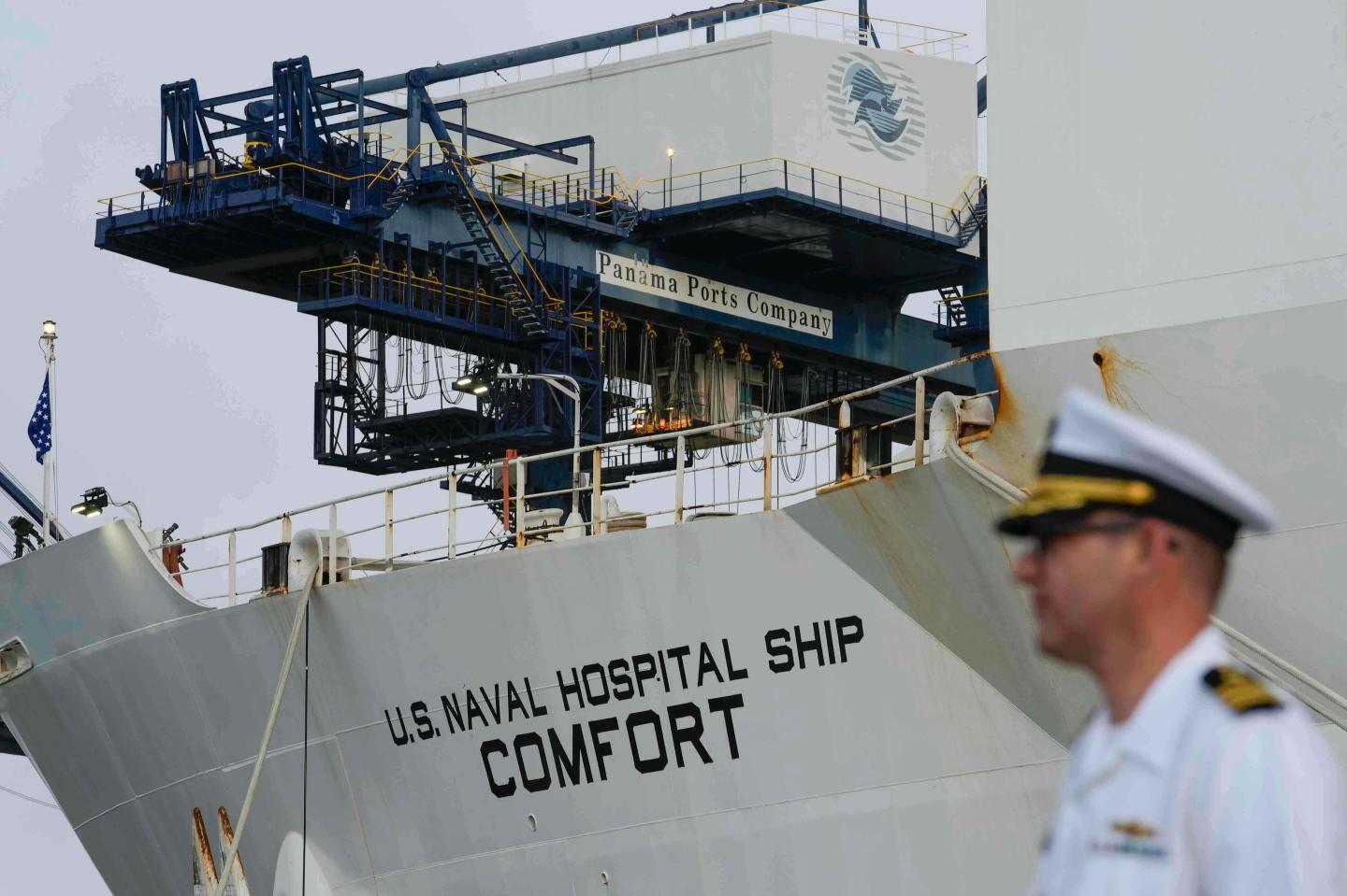 A sailor stands in front of the USNS Comfort.