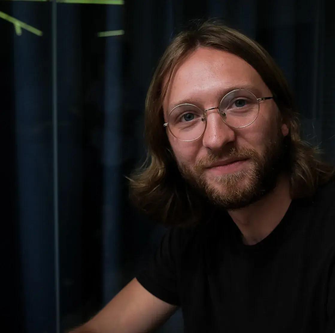 Man with glasses staring straight ahead.
