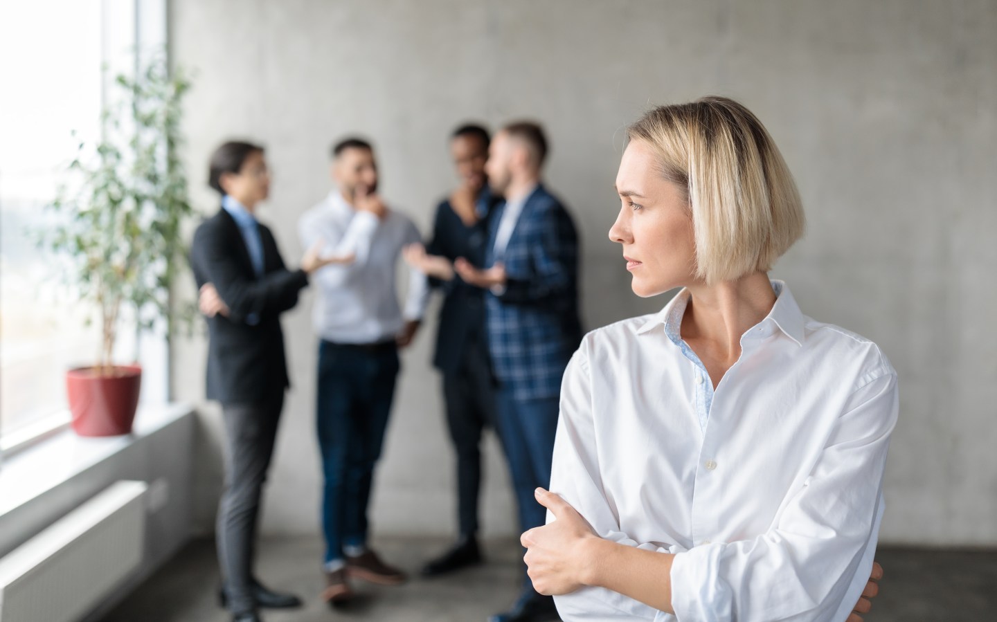 A woman stands as a group of her colleagues speaks.