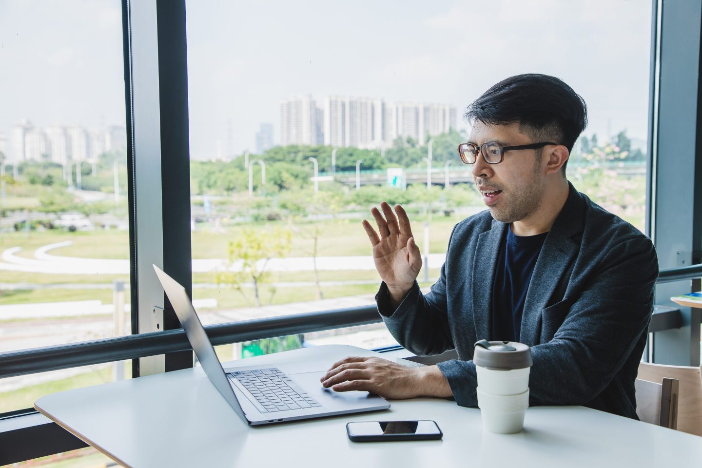Man wearing a suit awkwardly takes a video call on a laptop