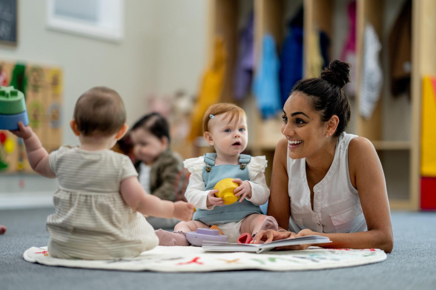 Babies play with their teacher in day care