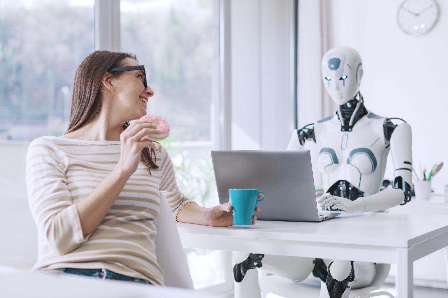 Lazy office worker eating donuts and wasting time, she is looking at the efficient AI robot working with a laptop