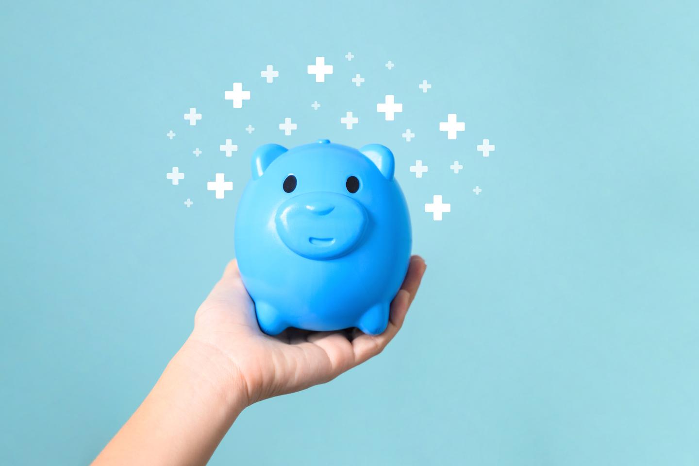 A person holding a blue piggy bank
