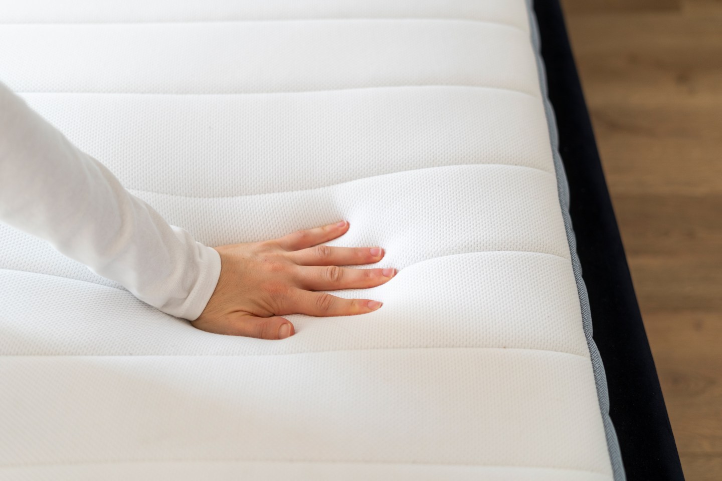A person pressing down on a mattress.