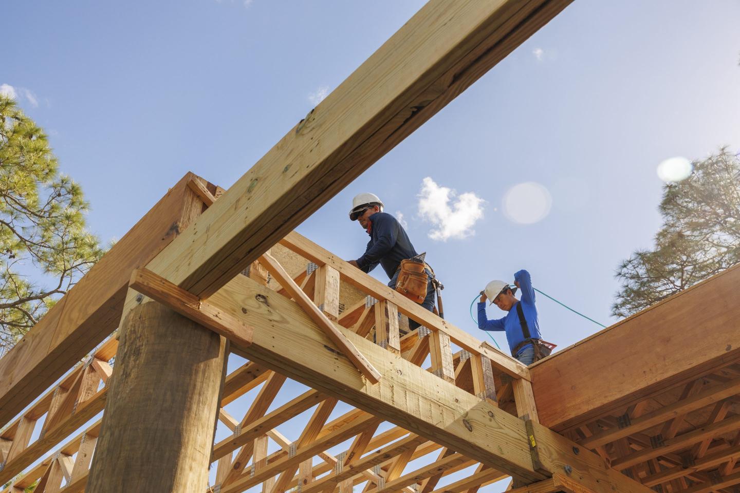 Low angle view of male carpenters working on rooftop of construction frame