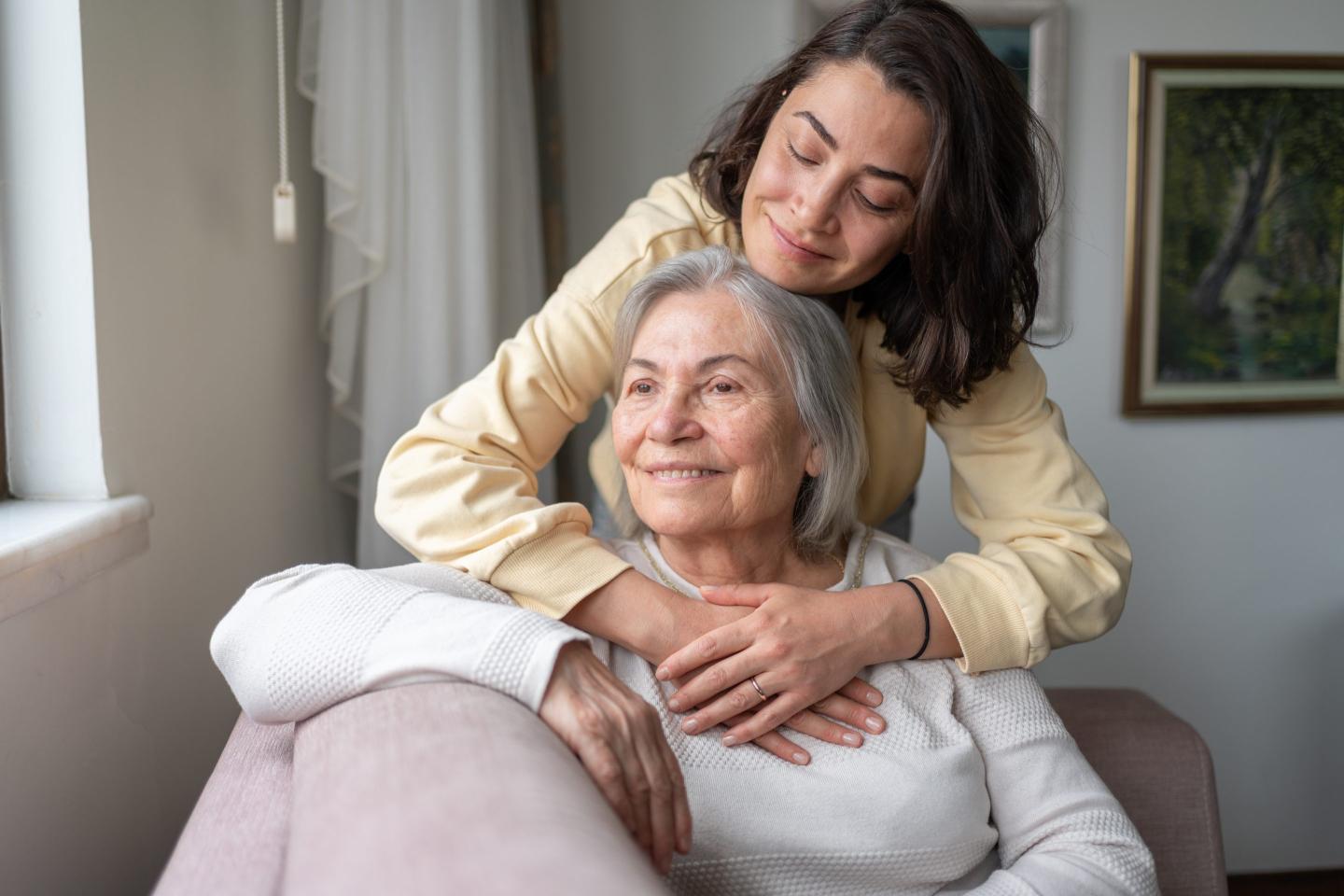 A woman hugs her senior mother.