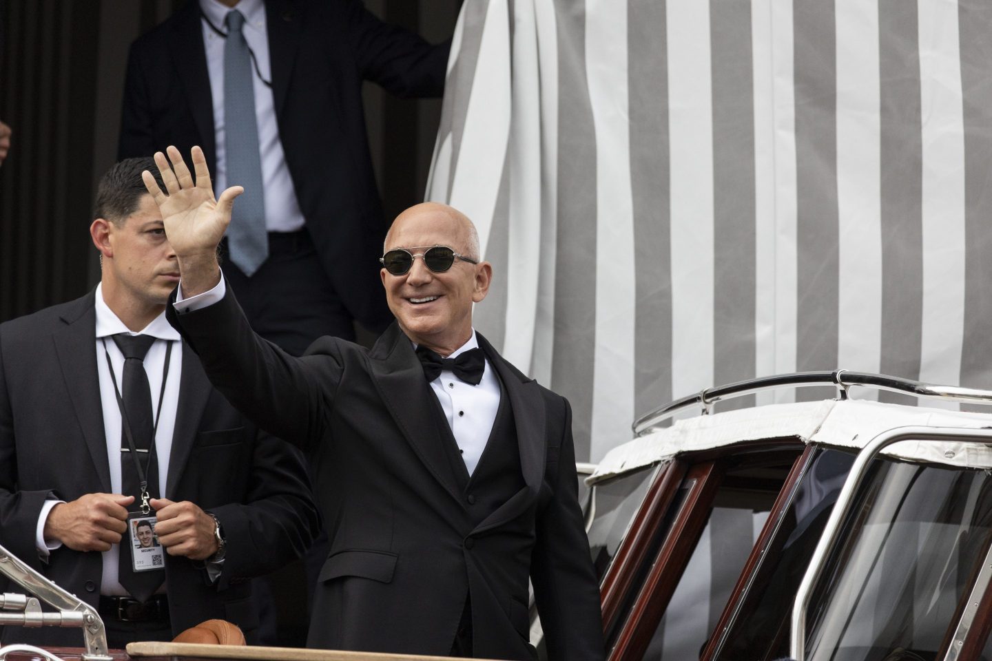 Jeff Bezos waving to a crowd and stepping on to a small boat in Venice