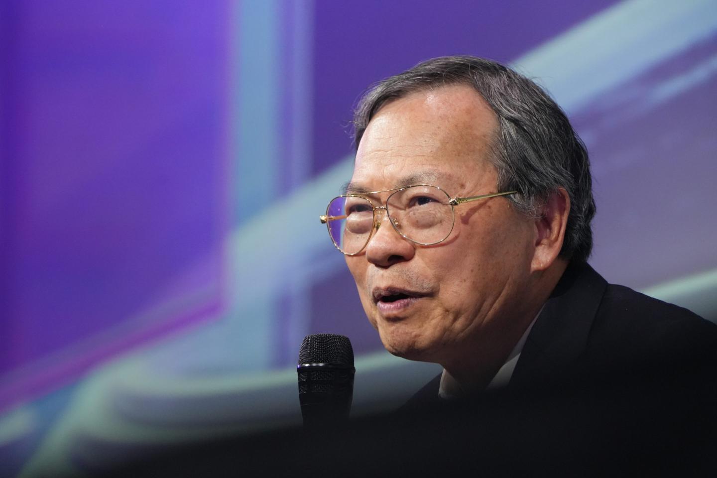 Man with glasses speaking into a microphone