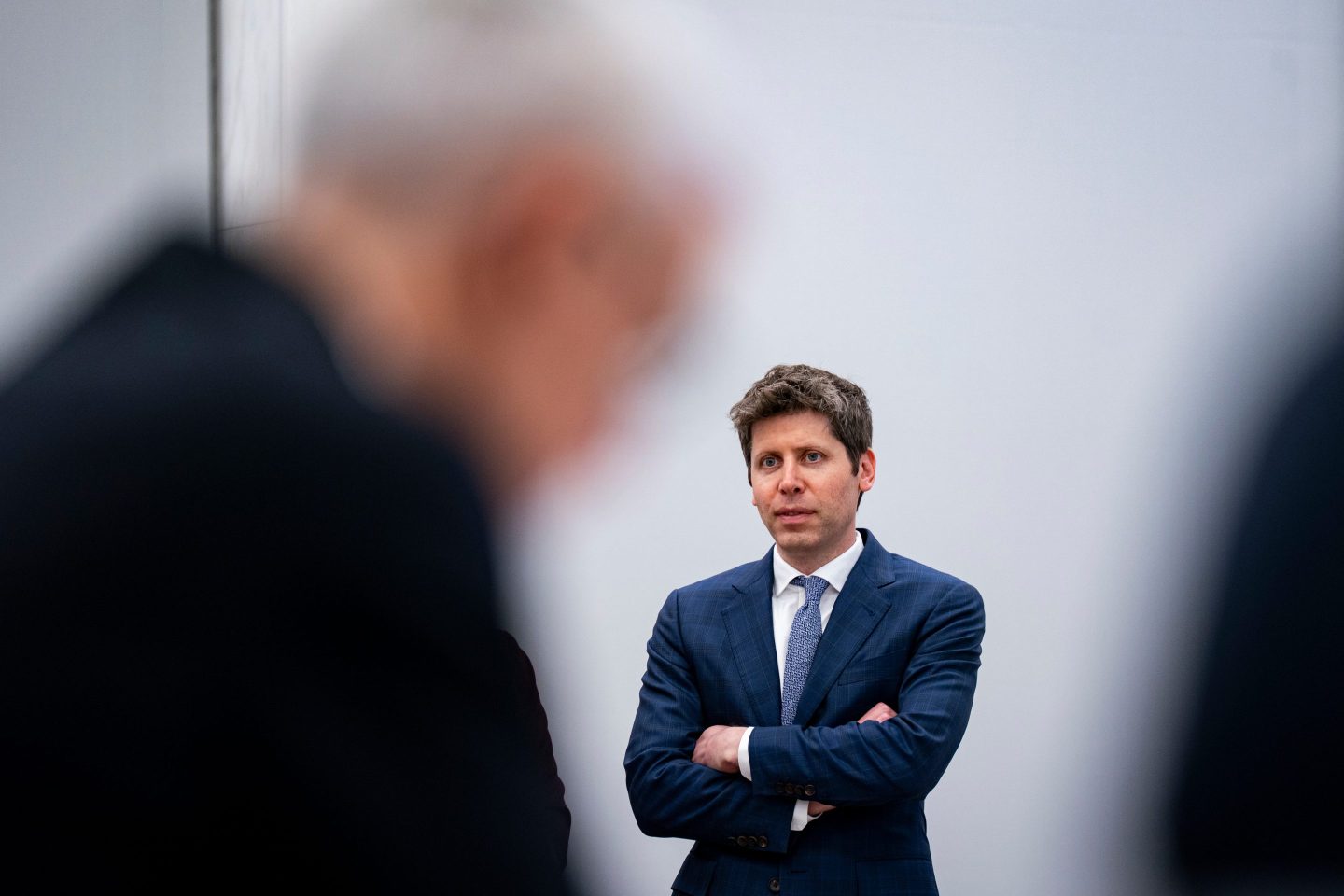 Sam Altman OpenAI CEO, standing with his arms folded.