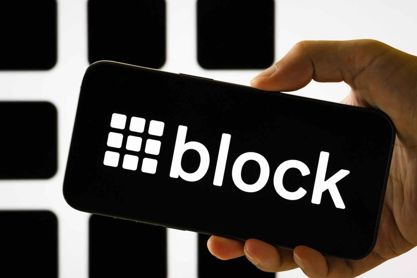 IN this photo illustration, a person holds a smartphone displaying the logo of Block Inc. (NYSE: SQ), a financial technology company