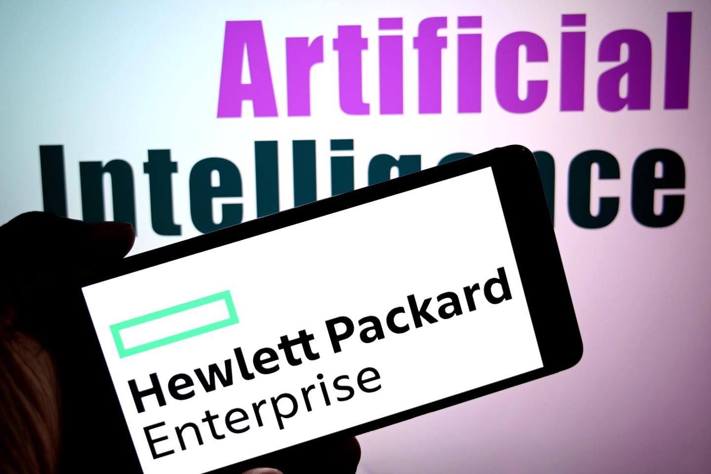 Illustration of the Hewlett Packard Enterprise logo is seen displayed on a smartphone with words 'Artificial Intelligence' in the background.